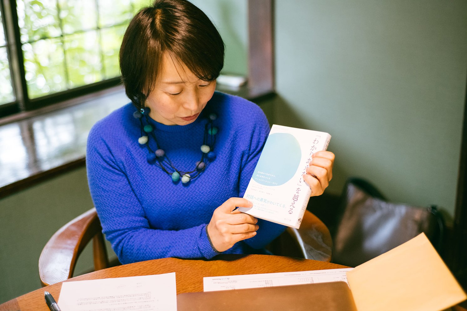 今井さんが翻訳に参加された書籍『「わかりあえない」を越える』を手に持つ今井さん | Make New Magazine「未来の定番」をつくるために、パナソニックのリアルな姿を伝えるメディア